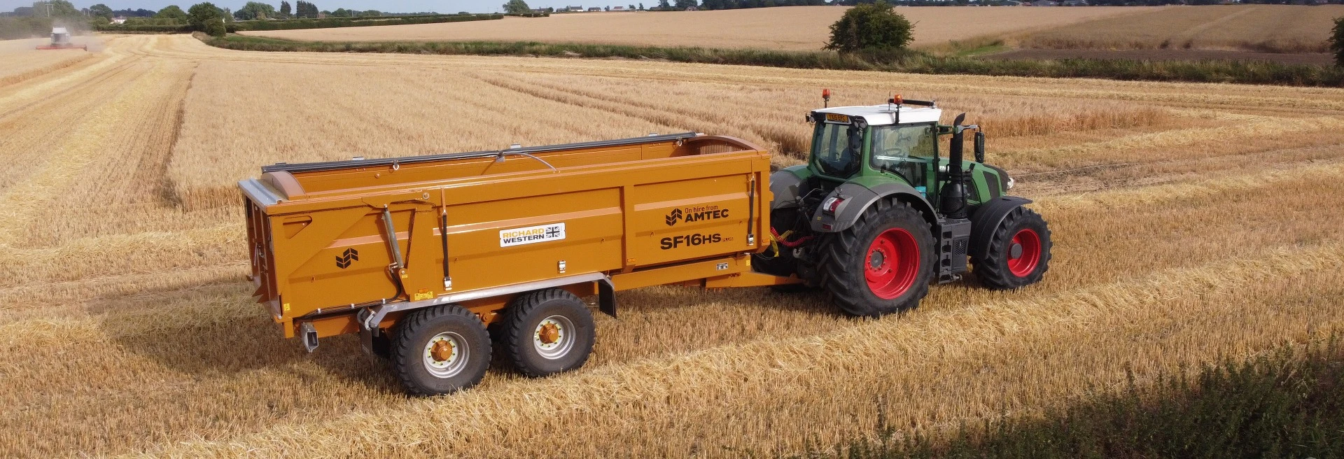 A richard Western silage trailer at work during harvest, being pulled by a green tractor.