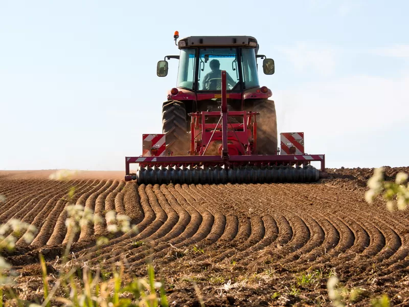 Tracteur dans un champ en train de semer du maïs.
